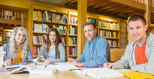 Group of students writing notes at library desk