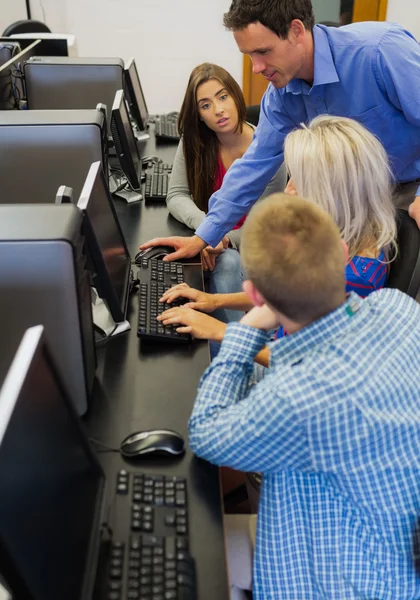 Teacher showing something on screen to student in computer room