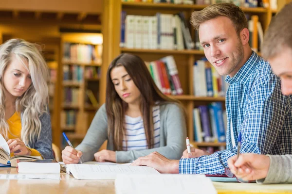 Smiling male student with friends at library desk