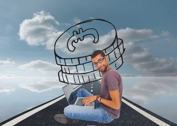 Man wearing glasses sitting on floor using laptop