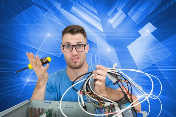 Confused young it professional with screw driver and cables