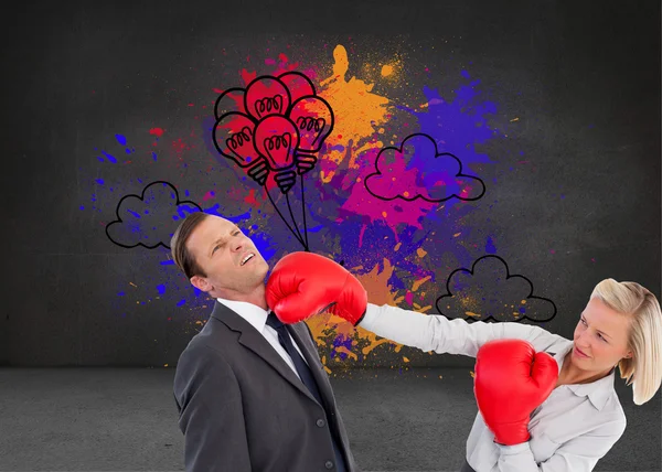 Businesswoman hitting colleague with her boxing gloves