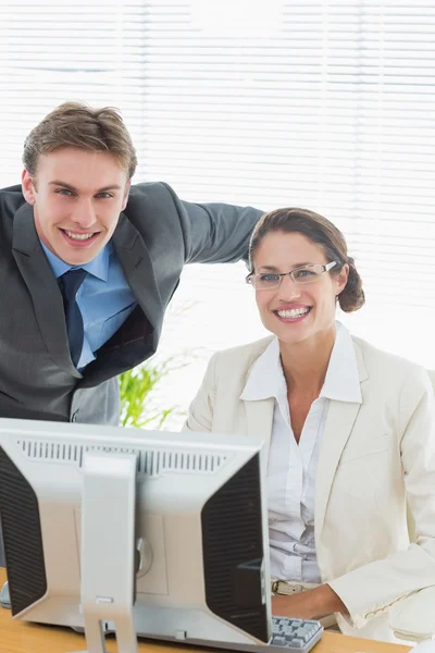 Confident smiling business couple with computer
