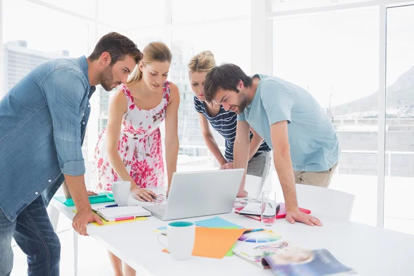 Casual business people using laptop together