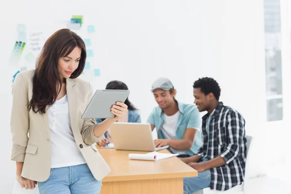 Woman using digital tablet with colleagues behind in office