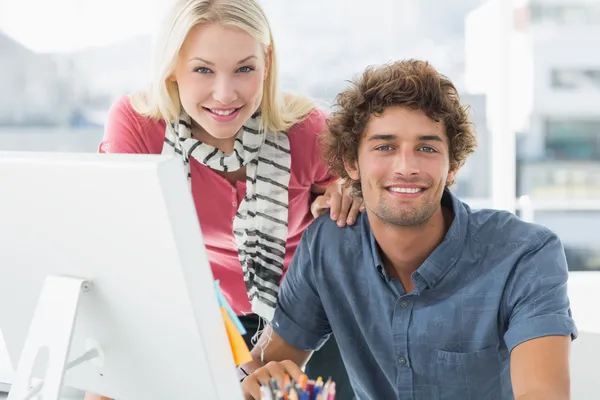 Smiling casual couple using computer in bright office