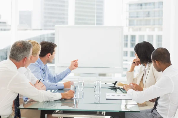 Business people looking at blank whiteboard in conference room
