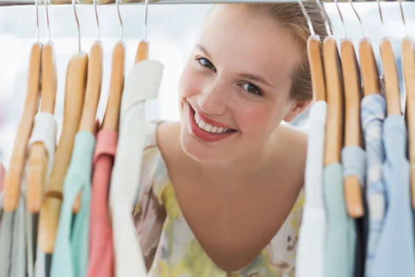Happy female customer amid clothes rack