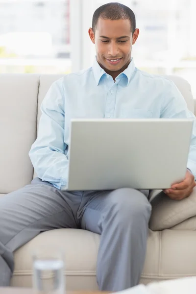 Happy businessman working on laptop on the sofa