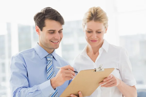 Smiling business team looking at clipboard together