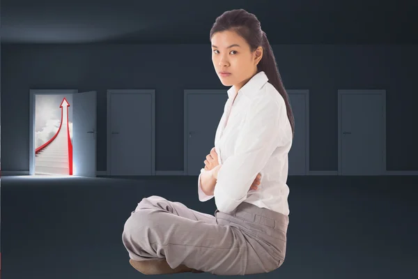 Composite image of businesswoman sitting cross legged with arms