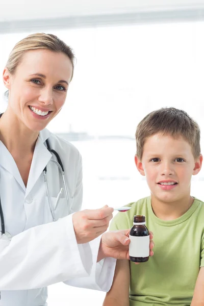 Doctor giving boy cough syrup
