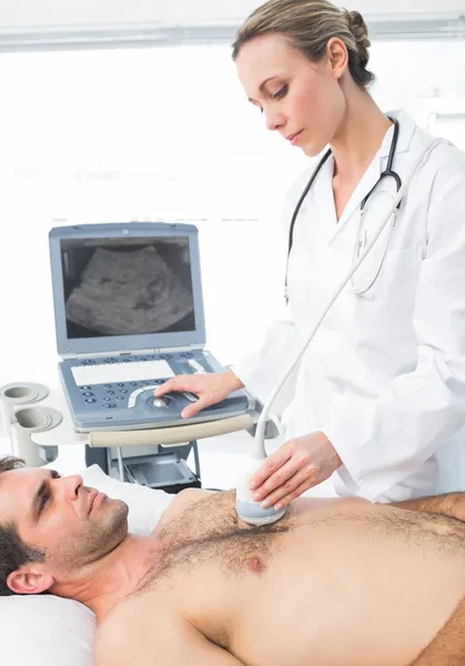 Cardiologist giving heart ultrasound to patient