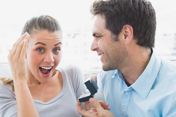 Delighted young couple getting engaged on the sofa