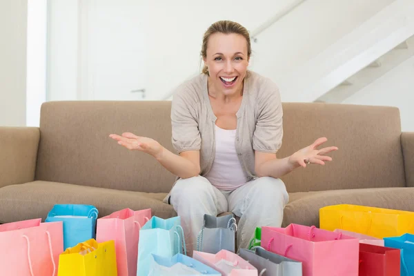 Excited woman looking at camera with many shopping bags