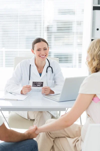 Confident doctor with expectant couple