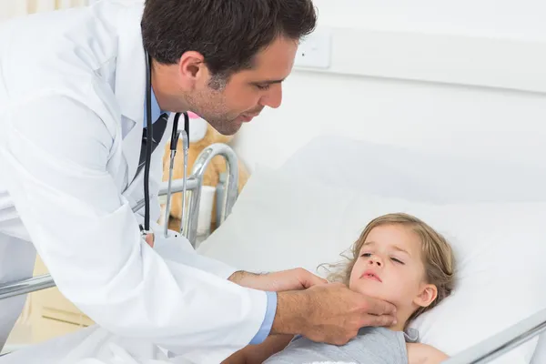Doctor checking thyroid glands of girl