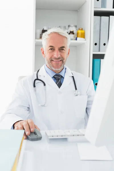 Confident male doctor with computer at medical office