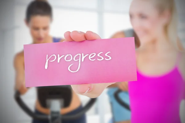 Woman holding pink card saying progress