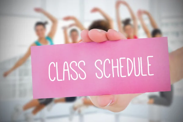 Woman holding pink card saying class schedule