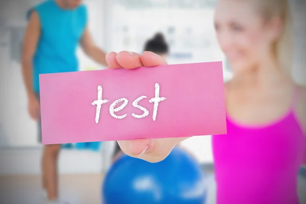 Woman holding pink card saying test