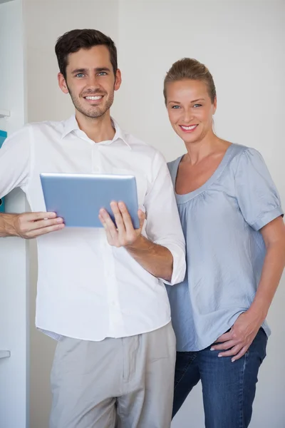 Casual business team smiling at camera man holding tablet