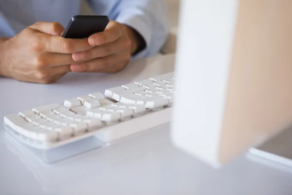 Businessman texting on phone at desk