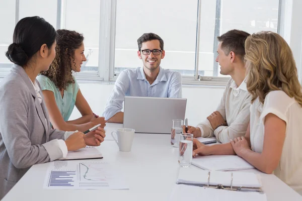 Casual boss smiling at camera dueing meeting with business team