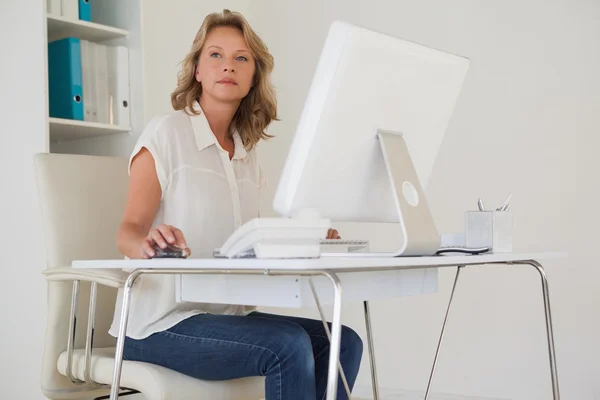 Casual businesswoman thinking at her desk