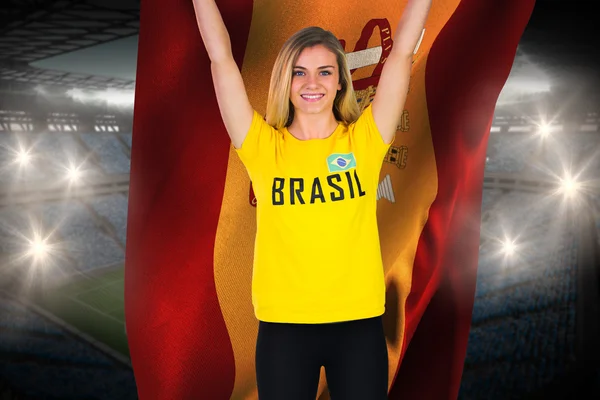 Composite image of excited football fan in brasil tshirt holding