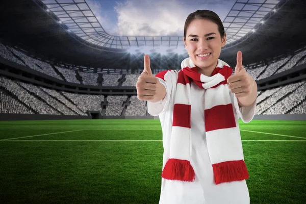 Football fan in white wearing scarf showing  thumbs up