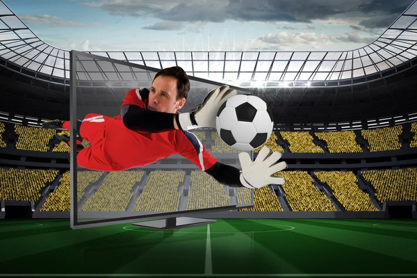 Composite image of fit goal keeper saving goal through tv