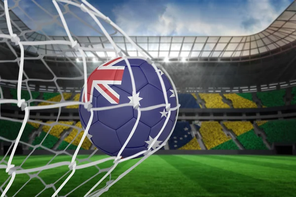 Composite image of football in australia colours at back of net