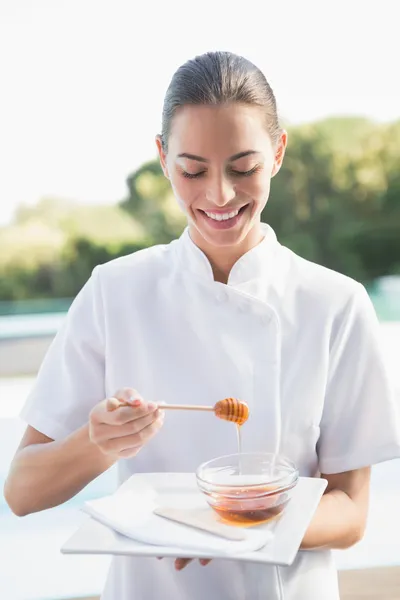 Beauty therapist holding plate with honey