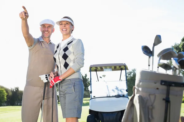 Golfing couple pointing with golf buggy