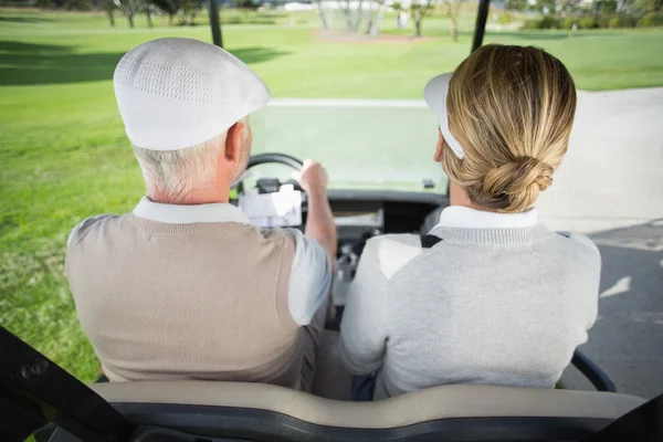 Golfing couple driving in golf buggy