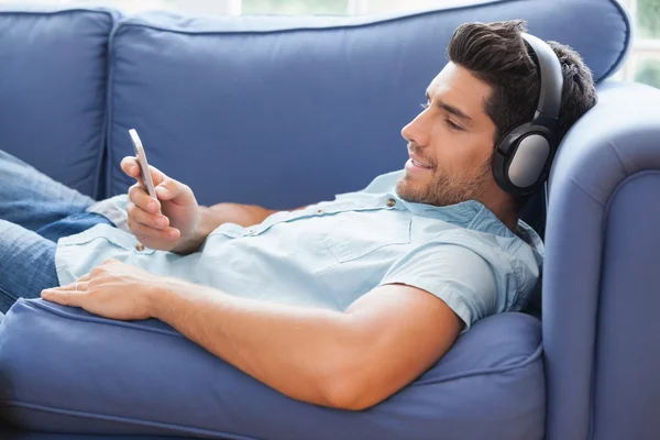 Man lying on the couch listening to music