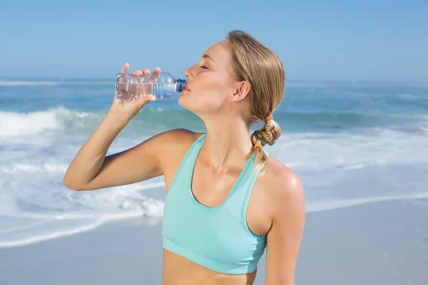 Fit woman on beach taking a drink
