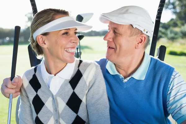 Golfing couple sitting in golf buggy