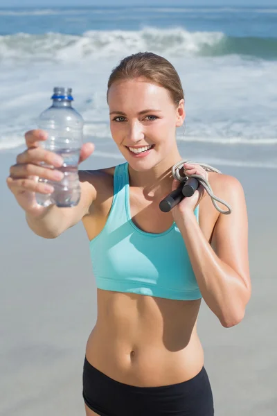 Woman holding water bottle and skipping rope