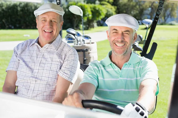 Golfing friends driving in golf buggy