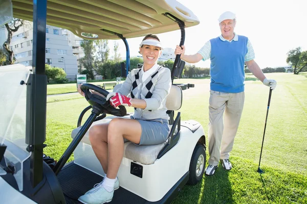 Golfing couple setting out for day on buggy