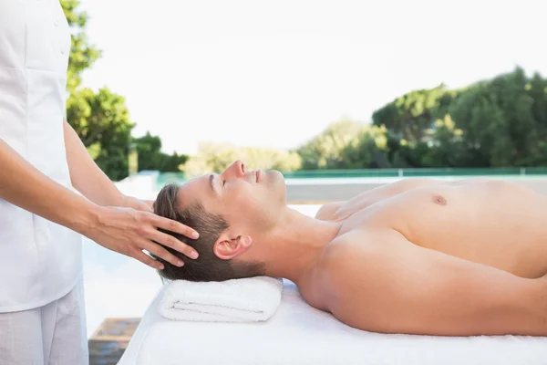 Man getting a head massage poolside