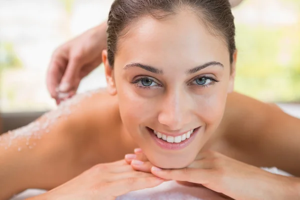 Therapist pouring salt scrub on womans back