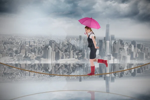 Businesswoman holding umbrella on tightrope