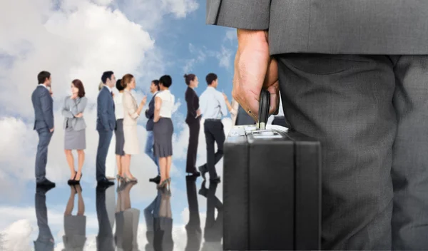 Businessman holding briefcase against business people
