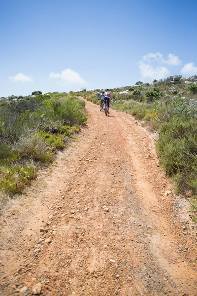 Couple cycling up mountain trail
