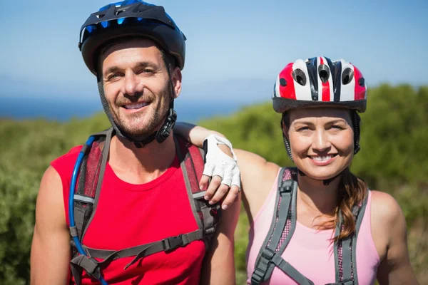 Active couple cycling in the countryside smiling at camera