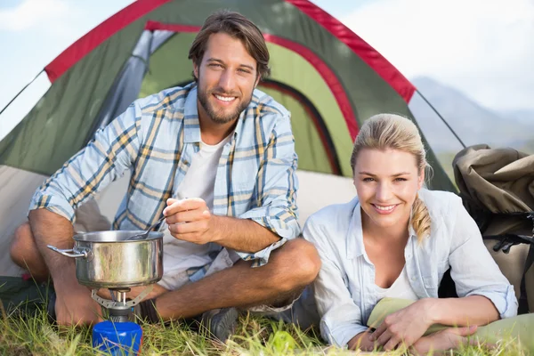 Happy couple cooking on camping stove