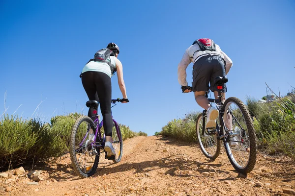 Active couple cycling uphill on a bike ride in the country